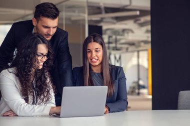 İş ekibi dizüstü bilgisayar kullanarak proje üzerinde işbirliği yapıyor. Güncel ofis ortamında sıradan iş arkadaşları birlikte çalışıyor. Takım çalışması konsepti