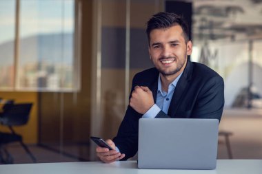 Çağdaş ofiste dizüstü bilgisayarda çalışan adam.