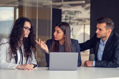İş ekibi dizüstü bilgisayar kullanarak proje üzerinde işbirliği yapıyor. Güncel ofis ortamında sıradan iş arkadaşları birlikte çalışıyor. Takım çalışması konsepti