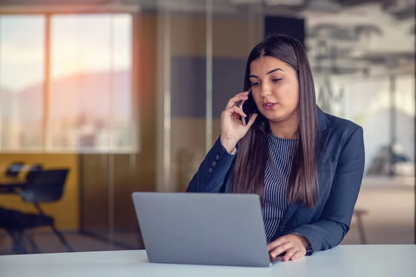 Poważna Bizneswoman Rozmawiająca Przez Telefon Komórkowy Biurze Pracująca Przy Komputerze — Zdjęcie stockowe