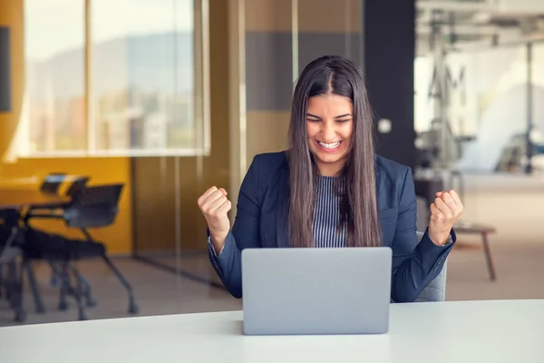 在办公室工作的年轻的黑发女人 手握手提电脑 做着积极的手势 微笑着竖起大拇指 快乐地工作着 快乐的表达和胜利的姿态 — 图库照片