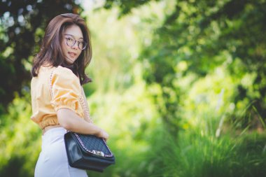 Güneşli bir günde doğada duran yeniyetme genç kızın yaz portresi. Genç zayıf, güzel kadın gülümsüyor ve kameraya bakmak için döndü. Yaz tatili, güneşli, eğlenceli ve pozitif bir konsept..