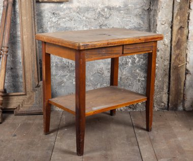 Eski tarz. Kirli bir odada, diğer eski eşyalarla dolu bozuk eski bir masa.