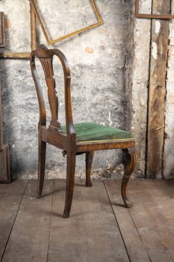 Eski tarz. Kirli bir odada, diğer eski püskü eşyalarla birlikte kırık bir sandalye.