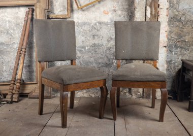 Kirli bir odada, eski bir meşe sandalyesi diğer eski eşyaların yanında duruyor.