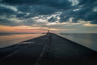 Gün batımında deniz feneriyle dramatik gökyüzünün uzun pozlama görüntüsü