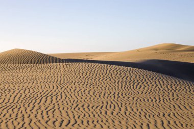 Gran Canaria 'daki Maspaloma Kumulları. Desenli kum tepecikleri, gölgeler ve soluk ayak izleri. Minimalist çöl manzarası. Doğa, seyahat ya da minimalist projeler için mükemmel.