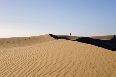 Gran Canaria 'daki Maspaloma Kumulları. Desenli kum tepecikleri, gölgeler ve soluk ayak izleri. Minimalist çöl manzarası. Doğa, seyahat ya da minimalist projeler için mükemmel.