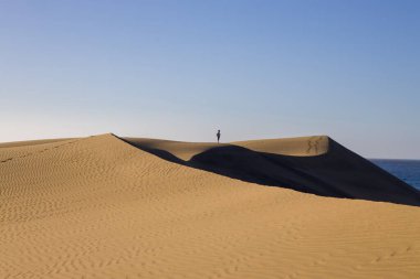 Gran Canaria 'daki Maspaloma Kumulları. Desenli kum tepecikleri, gölgeler ve soluk ayak izleri. Minimalist çöl manzarası. Doğa, seyahat ya da minimalist projeler için mükemmel.