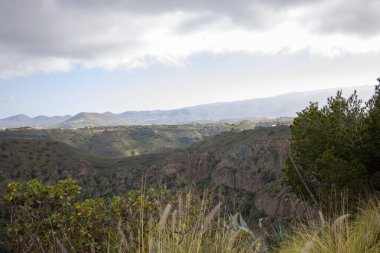 Engebeli dağ manzarası Bandama Caldera, Gran Canaria, kayalık ya da çıkıntılı. Açık mavi gökyüzü ve seyrek bitki örtüsü.