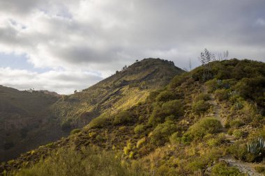 Engebeli dağ manzarası Bandama Caldera, Gran Canaria, kayalık ya da çıkıntılı. Açık mavi gökyüzü ve seyrek bitki örtüsü.