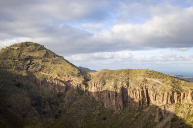 Engebeli dağ manzarası Bandama Caldera, Gran Canaria, kayalık ya da çıkıntılı. Açık mavi gökyüzü ve seyrek bitki örtüsü.