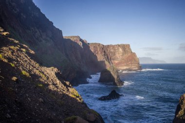 Ponta de Sao Lourenco 'daki gök mavisi okyanusun üzerinde dramatik uçurumlar yükselir. Dalgalar kayalık oluşumlara çarpar, güneşli bir günde doğal güzellikleri sergiler..