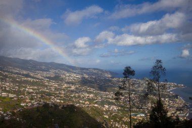 Ziyaretçiler, deniz seviyesinden 580 metre yukarıda bulunan Madeira Cabo Girao Skywalk 'tan panoramik manzaraların keyfini çıkarıyorlar. Aşağıdaki bereketli tepeler ve büyüleyici sahil kasabaları üzerinde canlı bir gökkuşağı yayları..