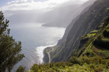 Okyanusa bakan Madeira kıyı kayalıkları. Sahil boyunca dolambaçlı bir yolu olan manzaralı bir yer. Seyahat, doğa ve manzara temaları için ideal.