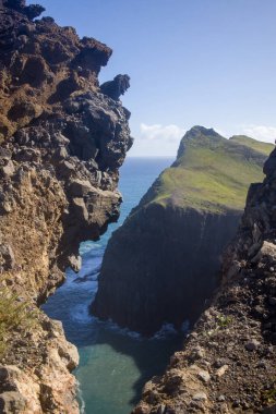 Yürüyüşçüler, Ponta de Sao Lourenco engebeli uçurumlarının ve Atlantik Okyanusu 'nun turkuaz sularının açık gökyüzü altında öğle güneşinin tadını çıkarıyorlar..
