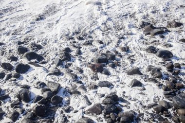 Köpüklü dalgalar Madeira kıyısı boyunca karanlık volkanik kayalara çarpar. Güneş ışığı bu çarpıcı adanın doğal güzelliğini ve engebeli kıyı şeridini yakalıyor..