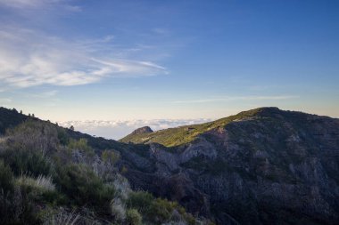 Madeira 'nın nefes kesen dağları ılık güneş ışığı ve yumuşak bulutlarla vurgulanır. Manzara çeşitli ve yemyeşil. Altın saat boyunca huzurlu bir atmosfer sunuyor..