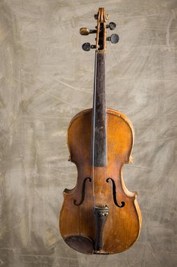 Antika bir keman dikey durur, kavisli gövdesini ve ince ahşap tahılını sergiler, yumuşak, sessiz bir arka planda durur. İşçiliği zengin bir müzik tarihini yansıtıyor..