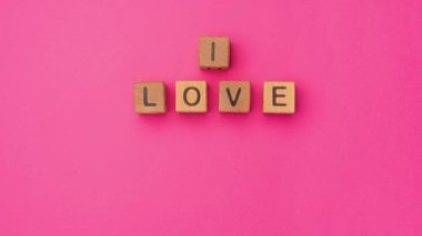Stop-motion wooden cubes with the phrase I Love You Baby on an empty colorful pink background. Words of love are made of letters from wood for Valentines Day and for your girlfriend, boyfriend, wife