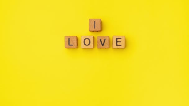 停止运动的木制立方体上有一句话 我爱你也许是在一个空旷的黄色背景上 情人节和你的女朋友 男朋友的情书是用木头写的 — 图库视频影像