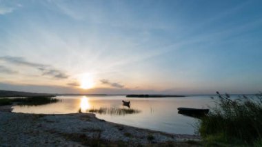 Ukrayna 'da Svityaz Gölü' nün balıkçı tekneleriyle kumsalda bulutlarla gün batımının zamanı..