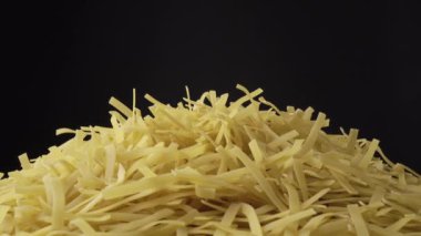 Pişmemiş Tagliatelle Lungo makarnası karanlık arka planda ağır çekimde dönüyor. Çiğ organik altın makarna. İtalyan yemeği, mutfak ve kültürü. Klasik kuru vermicelli yavaş döndürme