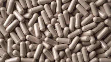 Bir grup Ginkgo Biloba tableti ya da kapsülü yavaşça döner. Hapların geçmişi. Üst manzara, düz yatış. Yüksek kalite 4k görüntü