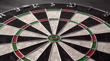 Bir dart, siyah ahşap arka planda bir dart tahtasının gözüne isabet eder. Mutlu galibiyet ve şans kavramı. Yakın çekim, açılı görünüm