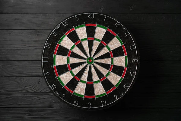 Siyah ahşap arka planda yeni klasik sisal dart tahtası. Kapat.