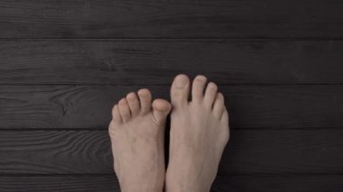 Siyah ahşap arka planda ya da zeminde bakımlı tırnakları olan erkek ayakları. Yakın çekim, üst görüş, bakış açısı