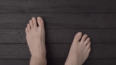 Siyah ahşap arka planda ya da zeminde son derece uzun ve son derece kesilmemiş tırnakları olan erkek ayakları. Yakın çekim, üst görüş, bakış açısı
