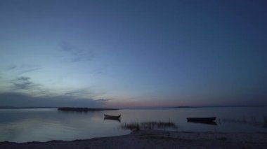 Kıyı, sahil, sazlıklar, balıkçı ahşap botları ve adanın bulunduğu güzel bir akşam ya da gece manzarası gün doğumunda ya da Ukrayna 'daki Svityaz Gölü' nde gün batımından sonra.