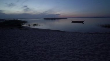 Akşam veya gece panoramik deniz kıyısı, sahil, sazlıklar, balıkçı tekneleri ve ada gün doğumunda ya da Ukrayna 'nın Svityaz Gölü' nde günbatımından sonra