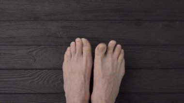 Siyah ahşap arka planda ya da zeminde son derece uzun ve son derece kesilmemiş tırnakları olan erkek ayakları. Yakın çekim, üst görüş, bakış açısı