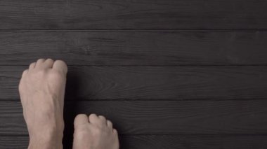 Siyah ahşap arka planda ya da zeminde son derece uzun ve son derece kesilmemiş tırnakları olan erkek ayakları. Yakın çekim, üst görüş, bakış açısı. Reklam metni için alanı kopyala