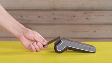 Modern kablosuz ödeme bankacılığı POS terminali, ahşap arka planda sarı masadaki dokunmatik ekranlı. NFC teknolojisi vasıtasıyla ulaşılmaz ödeme kavramı. Yakın plan, kenar görünüm, boşluk kopyala