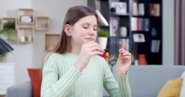 Oturma odasında masasında oturan, gözlük takan ve kameraya gülümseyen beyaz bir genç kızın portresi. Güzel liseli kız gözlük takıyor ve evde ödev yapıyor..