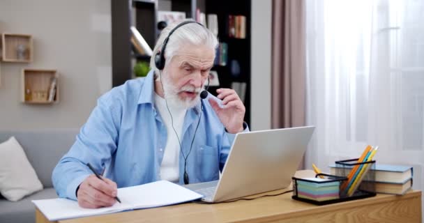 Kaukázusi Ősz Hajú Férfi Fülhallgatóban Online Beszél Laptop Webkamerával Miközben — Stock videók