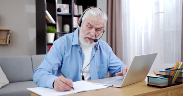Fehér Öregember Fülhallgatóban Online Beszél Laptop Webkamerán Keresztül Észrevesz Valamit — Stock videók