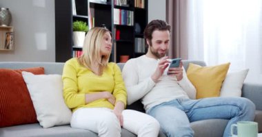 Beyaz adam evdeki kanepede otururken akıllı telefon kullanıyor. Güzel bir kadın kocasını telefonda mesajlaşırken ve sohbet ederken izliyor. İnternetteki erkek sohbetinde kadın tepkisi. Kapalı.