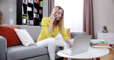 Şık, beyaz, meşgul, güzel bir kadın oturma odasında kanepede oturuyor ve dizüstü bilgisayarla mesajlaşıyor, cep telefonuyla konuşuyor. İçeride. Bilgisayarda çalışan ve cep telefonuyla konuşan serbest çalışan bir kadın..