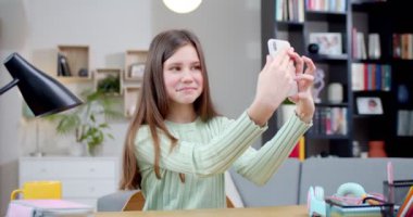 Mutlu kız selfie çekiyor, odada oturan arkadaşlarıyla sohbet ediyor. Telefonu çevrimiçi kullanıyorum. İnternetteki insanlarla konuşmak için iPhone 'da fotoğraf çeken genç bir kız. İnternet kavramı