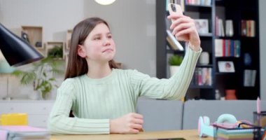 Heyecanlı genç kız telefonu tutuyor, selfie çekiyor, arkadaşlarıyla iletişim kuruyor, internette geziniyor. Liseli kız çocuk odasında telefon kullanarak fotoğraf yolluyor ve paylaşıyor. Teknoloji konsepti.