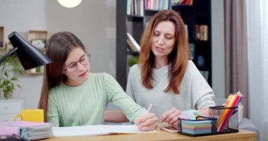 Anne ve çocuğu birlikte ev ödevi yapıyorlar. Liseli kız annesinden yeni şeyler öğreniyor ve birbirleriyle konuşuyor. Gözlüklü genç kız çocuk odasındaki masada ders çalışıyor. İlkokul konsepti