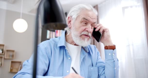 Homem Caucasiano Cabelos Grisalhos Sentado Mesa Sala Estar Falando Telefone — Vídeo de Stock
