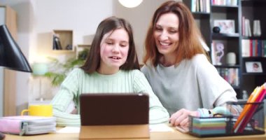 Mutlu gülümseyen kız ve anne online video görüşmesi yapıyor. Güzel, neşeli kız, internette konuşan ve el sallayan bir kadın. İnsanlarla Interent, tablet üzerinden konuşmak için araçlar. İletişim teknolojileri.