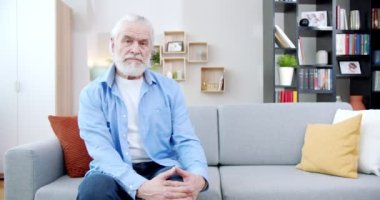 Düşünceli yaşlı adam oturma odasındaki kanepede huzur içinde oturuyor. Gri saçlı, sakallı, tişörtlü ve kot pantolonlu güzel bir son sınıf öğrencisi kameraya bakıyor, hayatı düşünüyor. Düşünme konsepti.