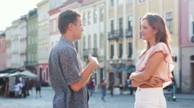 Kasaba sokaklarında birbirine aşık genç beyaz bir çift birlikte vakit geçirirken gülümsüyor ve birbirleriyle konuşuyor.