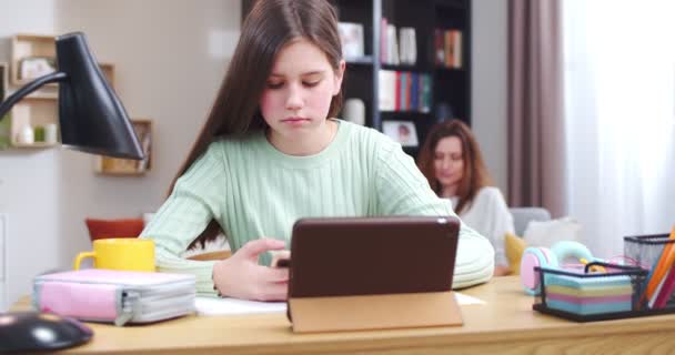 Focused Schoolgirl Doing Homework Using Phone Tablet Daughter Writing Essay — Stock Video